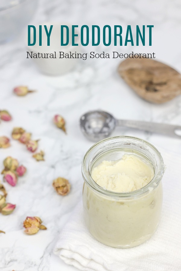 DIY deodorant in a glass jar on a white wash cloth with rose buds to the left and a steel measuring spoon behind it.