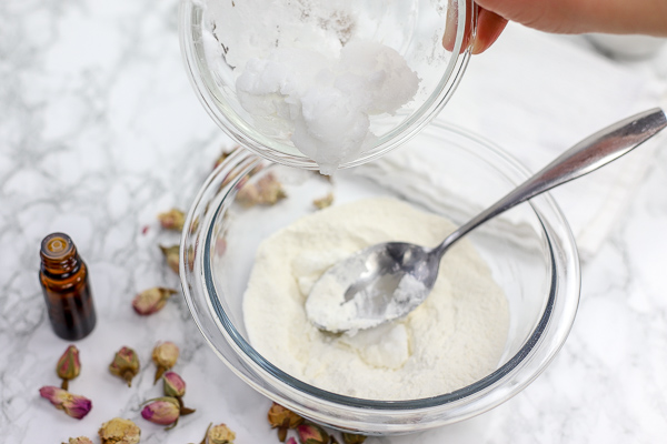 bowl of diy deodorant ingredients and a spoon. Coconut being adding to bowl