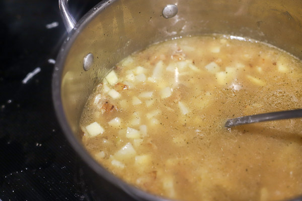 potatoes and broth simmering in a pot for baked potato soup