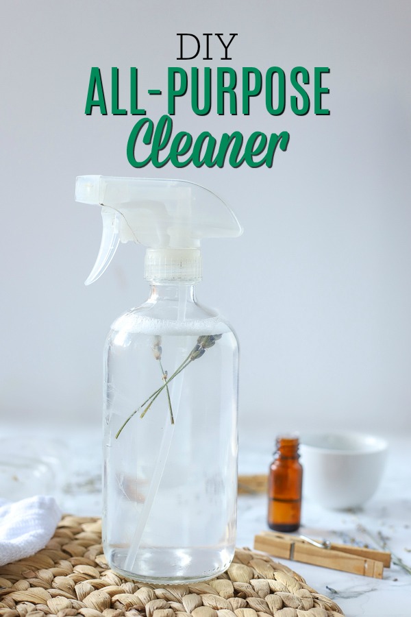 glass spray bottle of DIY all-purpose cleaner on a rattan place mat and ingredients around it