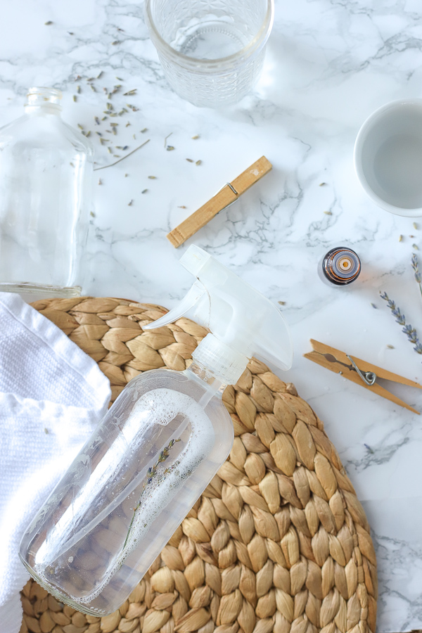 DIY All-Purpose cleaner on a rattan place mat with clothes pins and essential oils around it