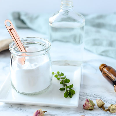 natural homemade toilet cleaner in a glass dish on a white plate with herbs