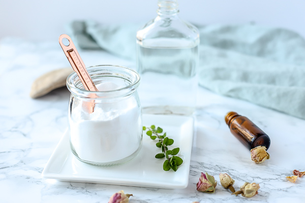 natural homemade toilet cleaner in a glass dish on a white plate with herbs