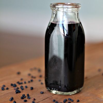 A Bottle of Elderberry Syrup with dried elderberries around
