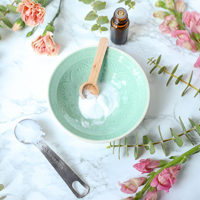 baking soda in a teal bowl with flowers around to make diy face scrub