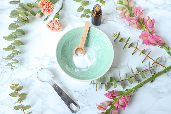 baking soda in a teal bowl with flowers around to make diy face scrub