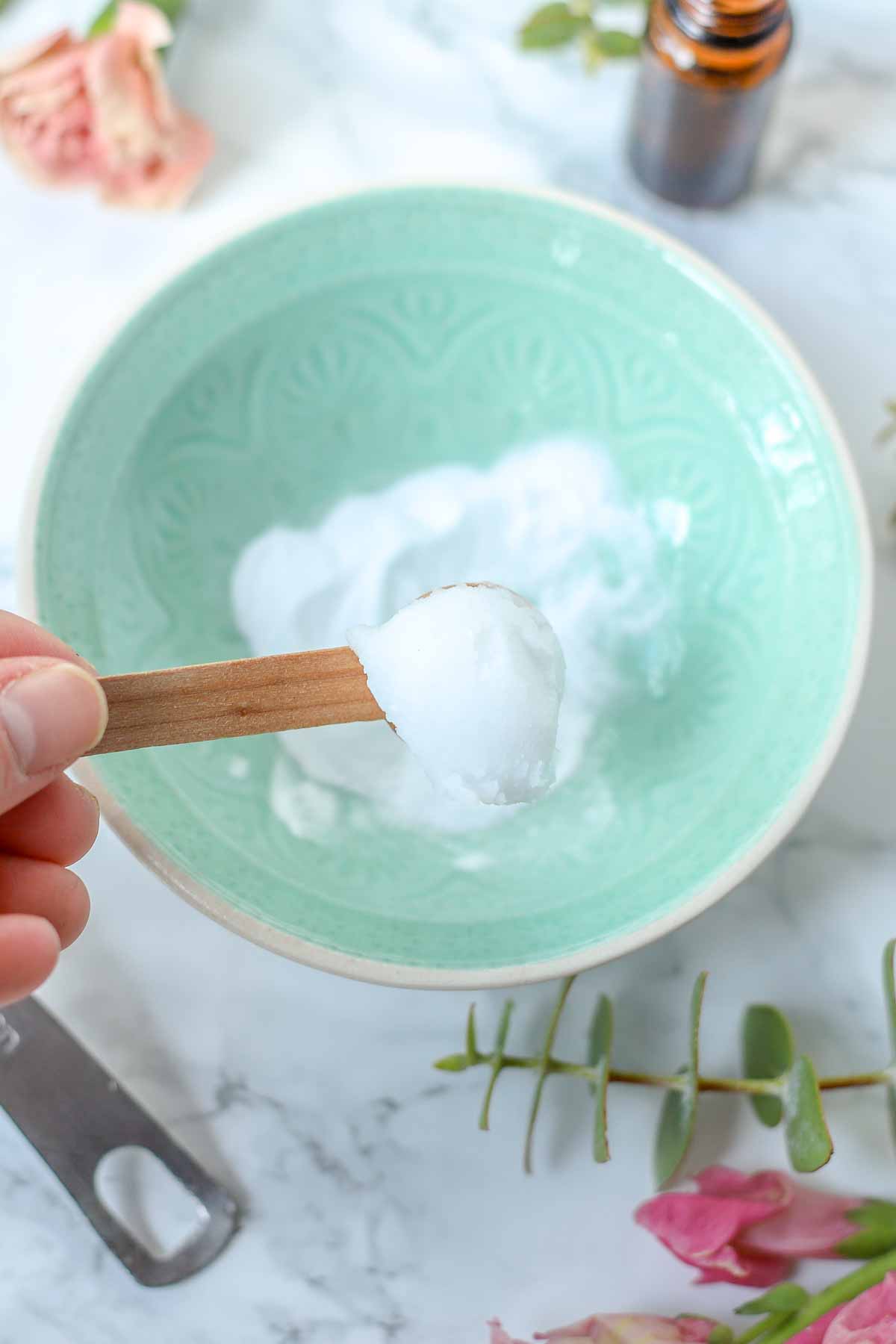 Mixing coconut oil, baking soda, and essential oil together in a bowl.