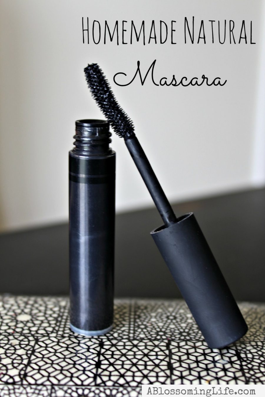 tube of natural homemade mascara on a black and white patterned plate