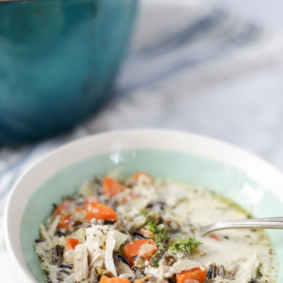 close up photo of chicken and wild rice soup with carrots and fresh herbs