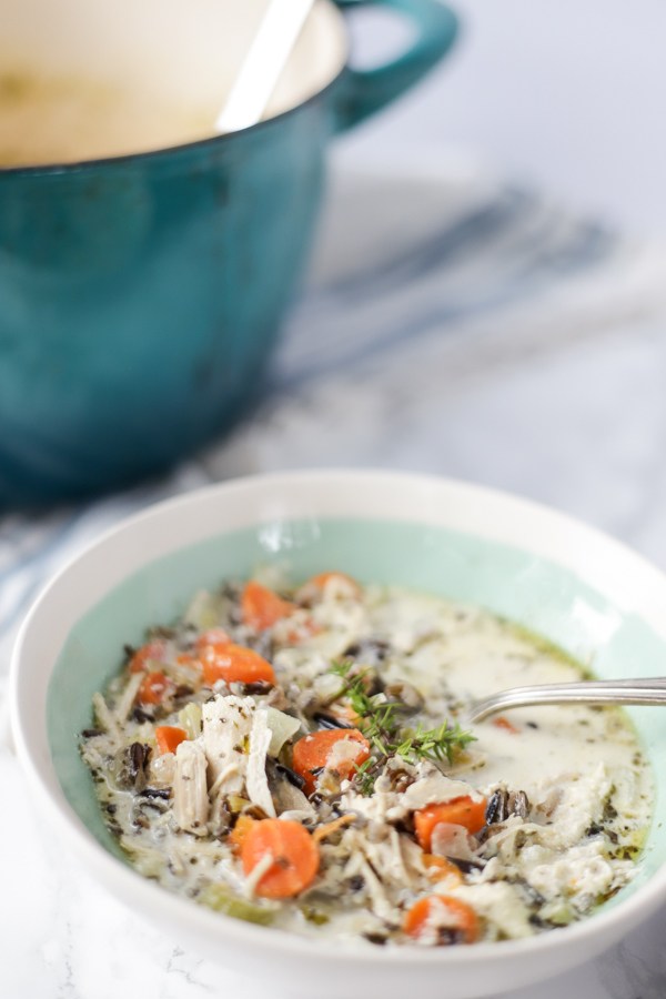 close up photo of chicken and wild rice soup with carrots and fresh herbs