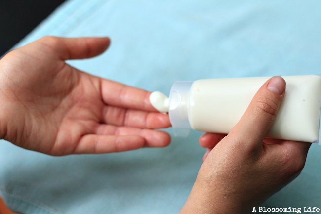 Natural homemade sunscreen in a squeeze bottle being squeezed onto hands