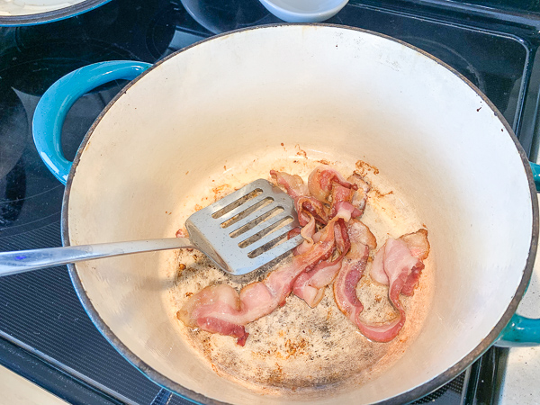 dutch oven with bacon cooking in it to make minestrone soup