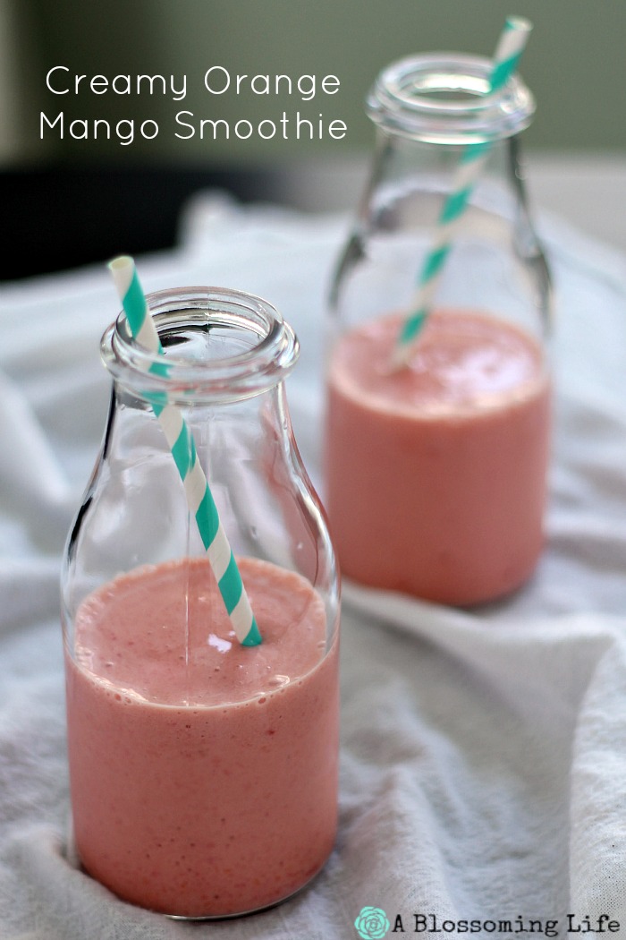 two orange mango smoothies in glass milk jars with stripped straws coming out.