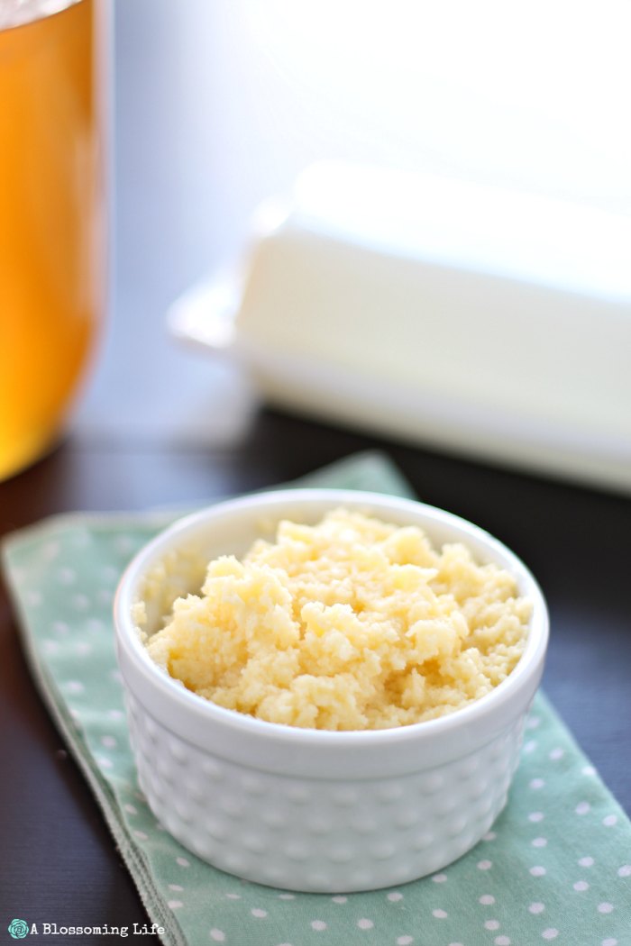 honey butter in a white dish on a green napkin with butter and honey behind it