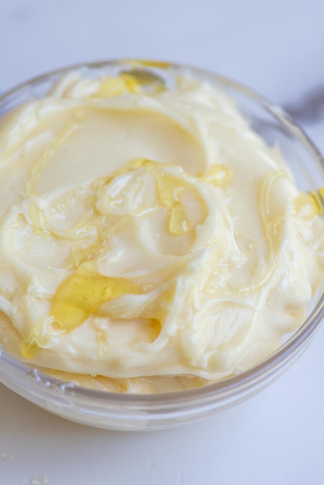 Whipped honey butter drizzled with extra honey in a glass bowl.