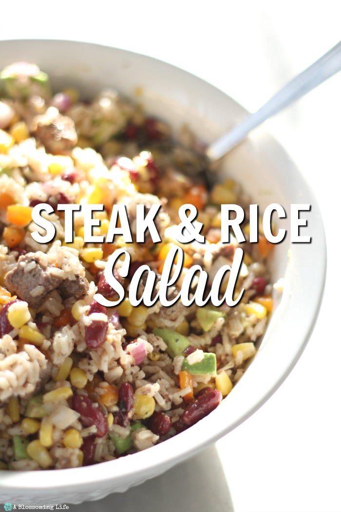 Steak rice salad in a white bowl with a spoon coming out