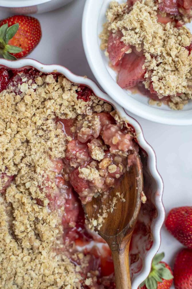 strawberry crumble with a scoop taken out and a spoon sitting in the dish.