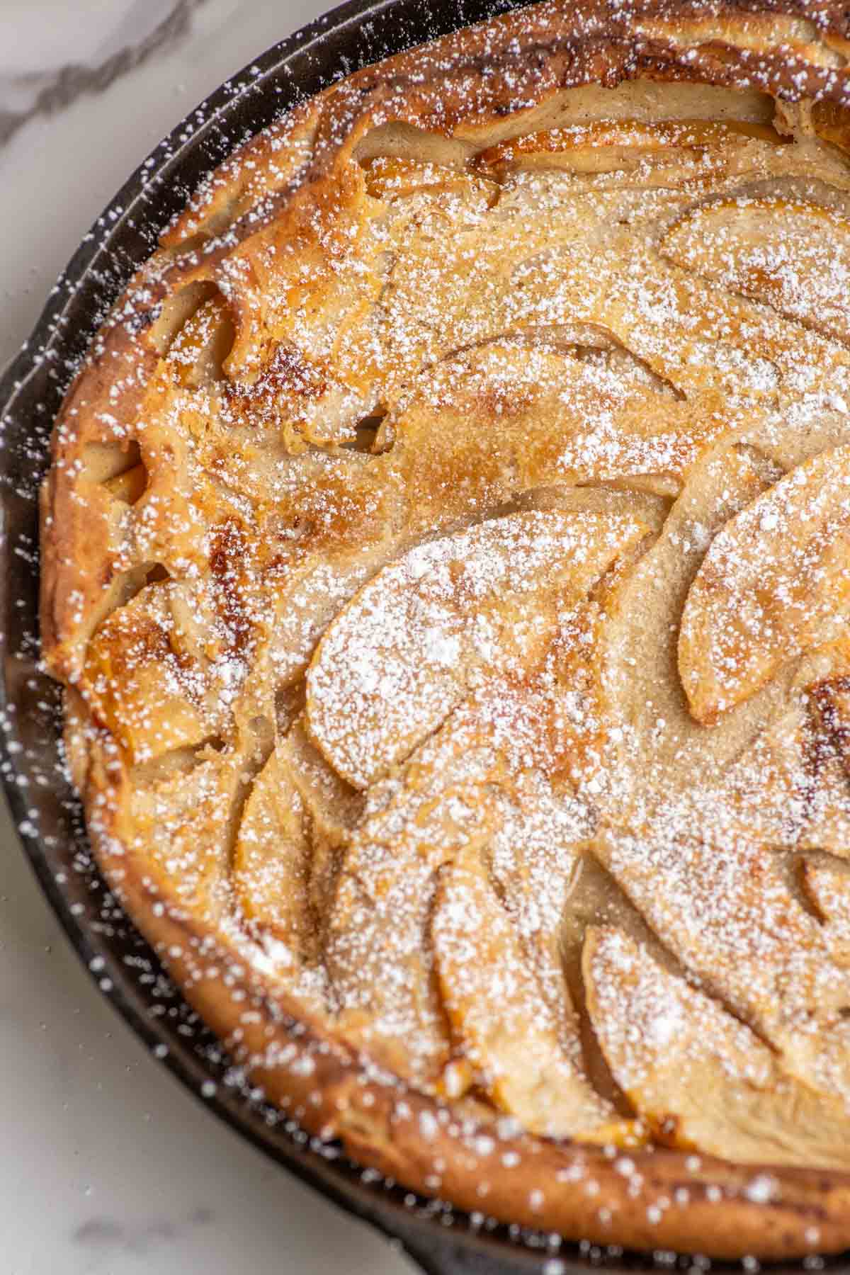 Close up of a apple Dutch baby pancake in a cast iron skillet.