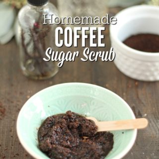 bowl of DIY coffee scrub with coffee grounds, jar of coconut oil, eucalyptus, and a jar of vanilla beans in the background.