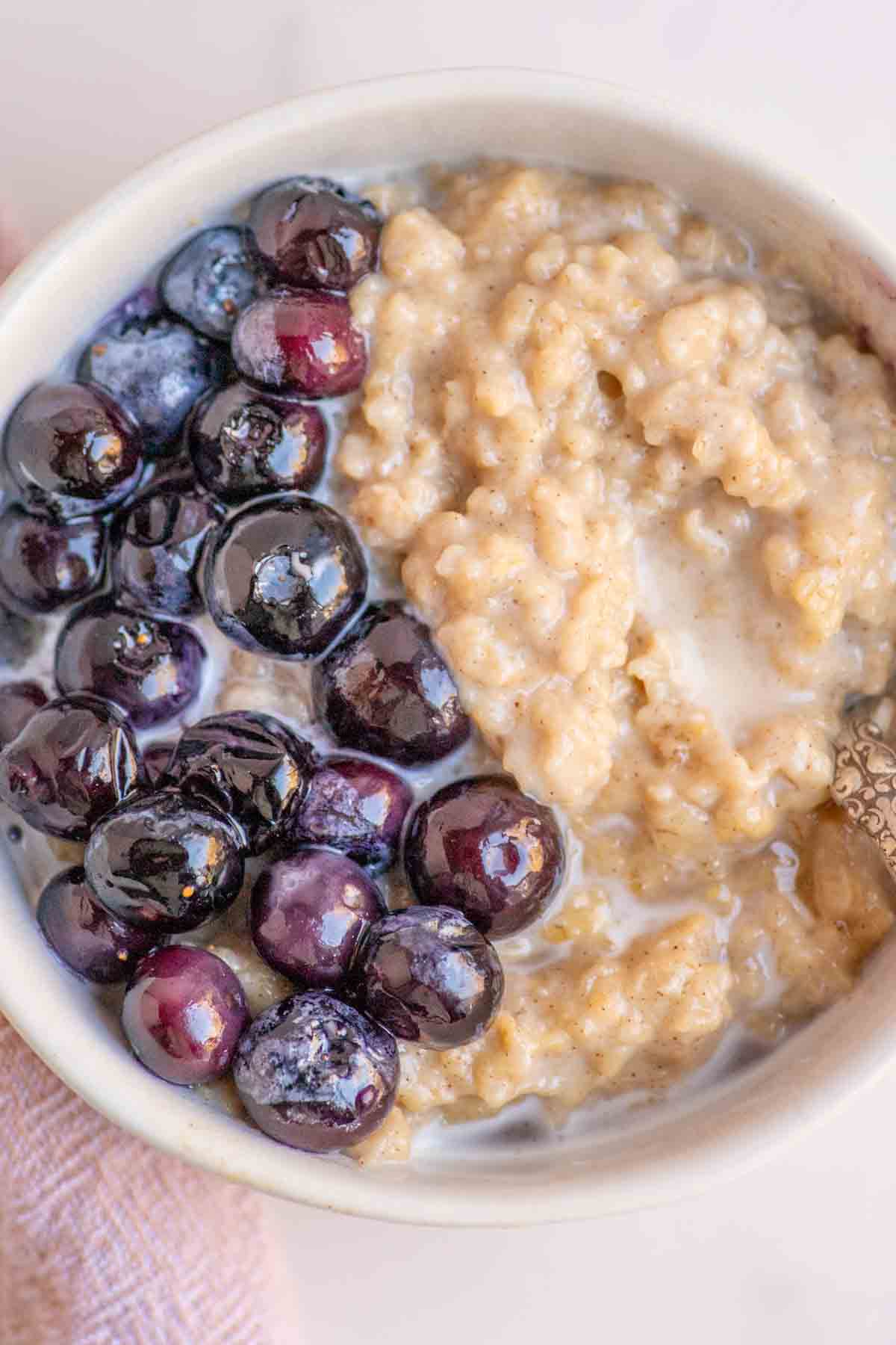 Overhead photo of custard oatmeal topped with blueberries and cream.