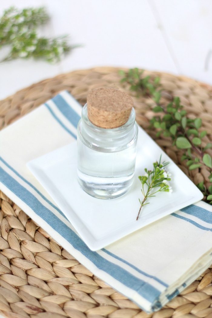 homemade mouthwash on a white plate over a blue and cream plate and rattan placemat