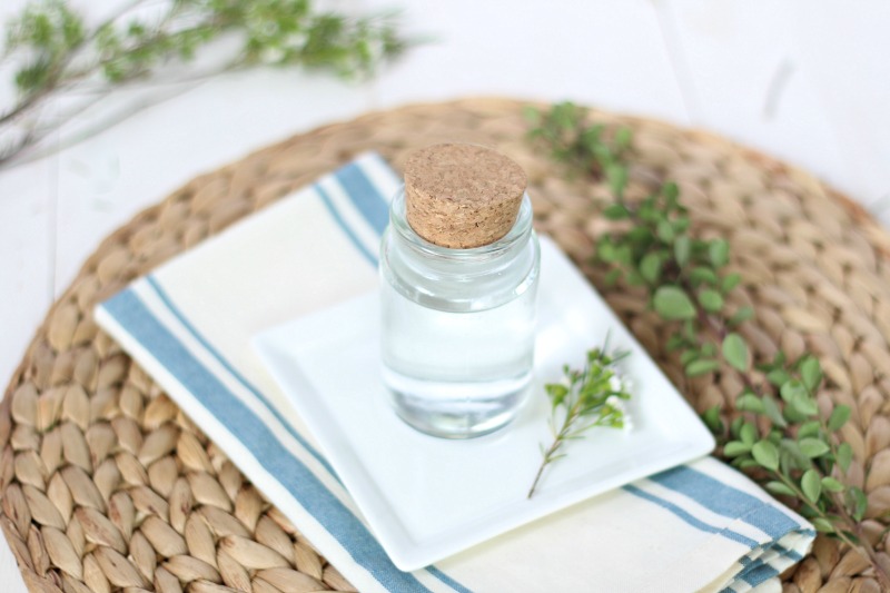 diy mouthwash in a glass jar on a white plate and rattan mat