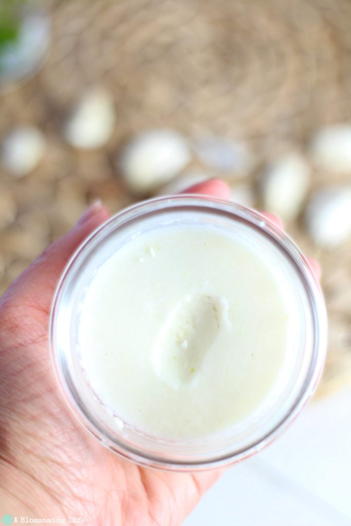 hand holding a jar of garlic salve with garlic cloves in the background