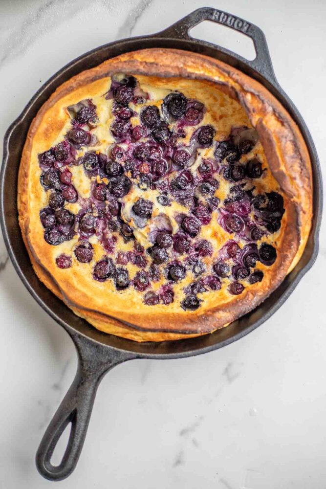 Blueberry dutch baby fresh from the oven in a cast iron skillet.