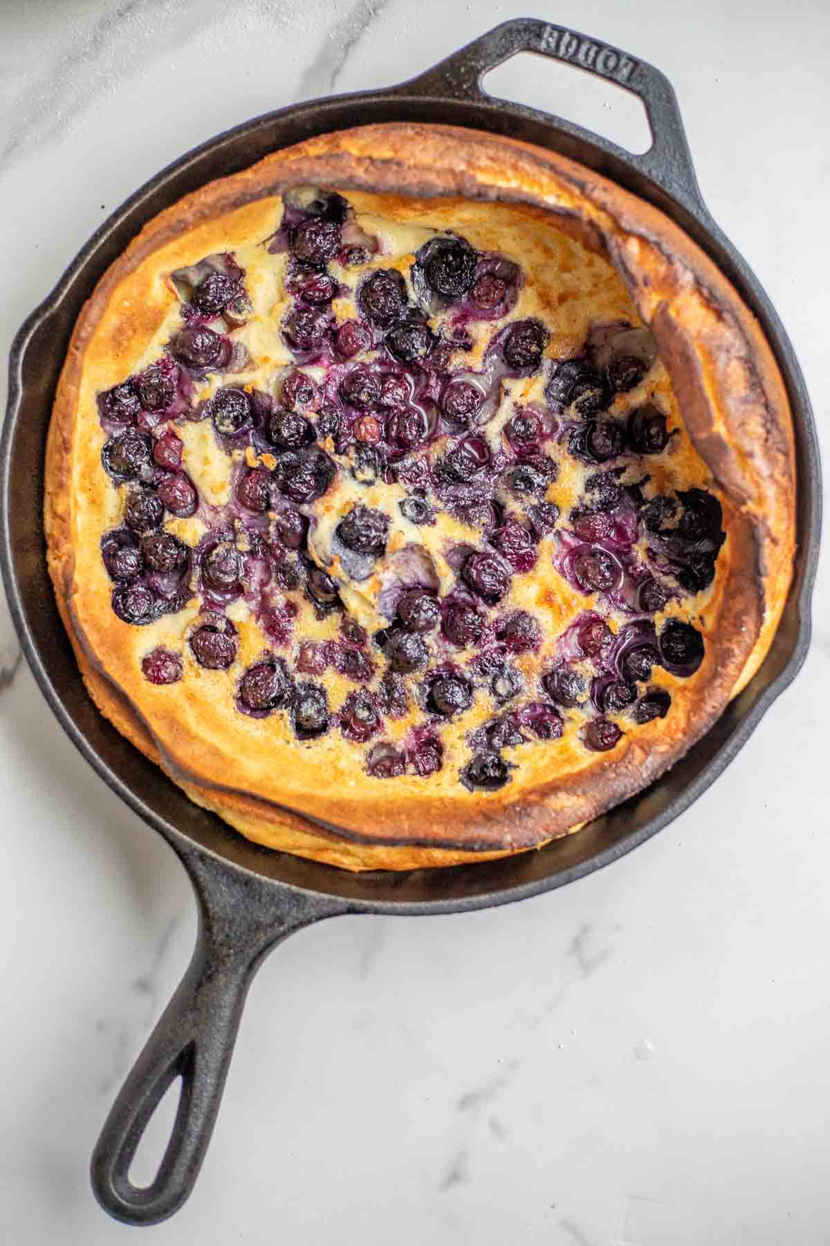 Blueberry dutch baby fresh from the oven in a cast iron skillet.
