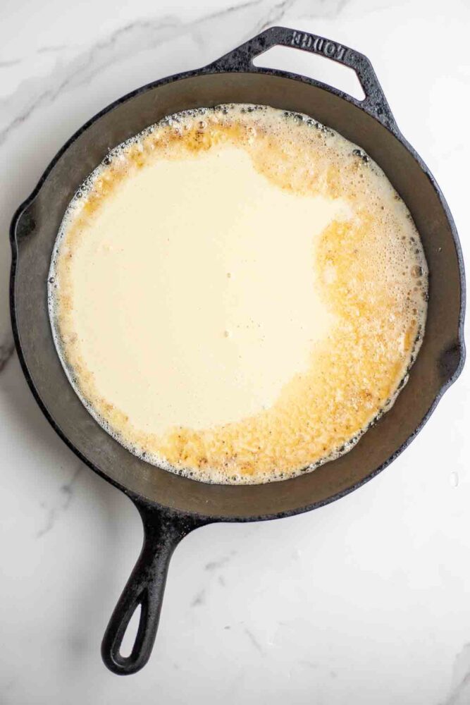 Pancake batter poured into a cast iron skillet.