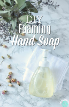 Foaming hand soap on a white wash clothes with eucalyptus leaves and dried roses to the left