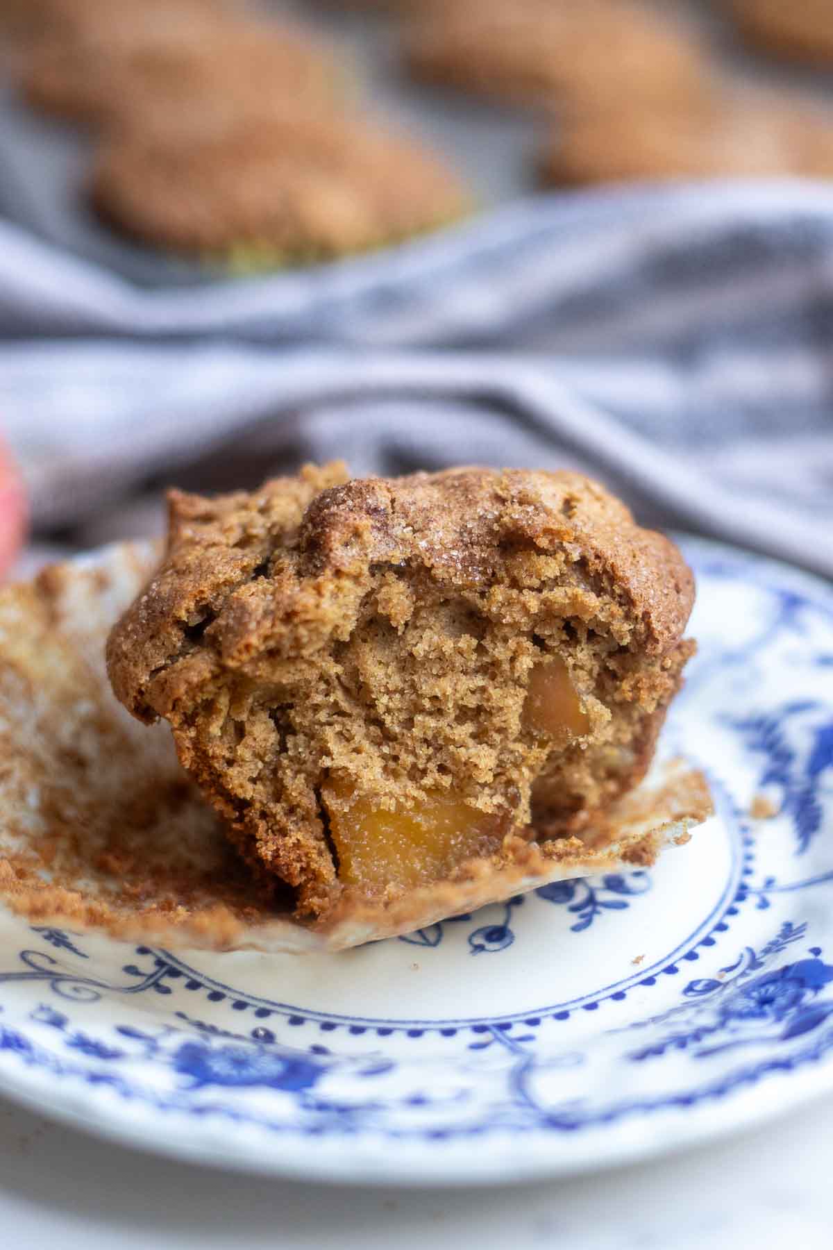 Gluten free apple muffins cut in half exposing chunks of apples. The muffin is on a blue and white floral plate.