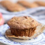 Gluten free apple muffins on a blue and white plate with more muffins in the background.