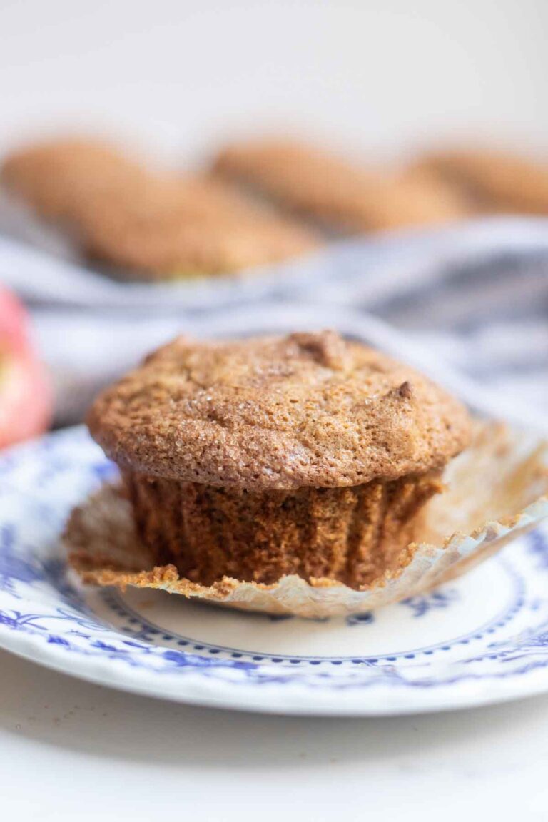 Gluten free apple muffins on a blue and white plate with more muffins in the background.