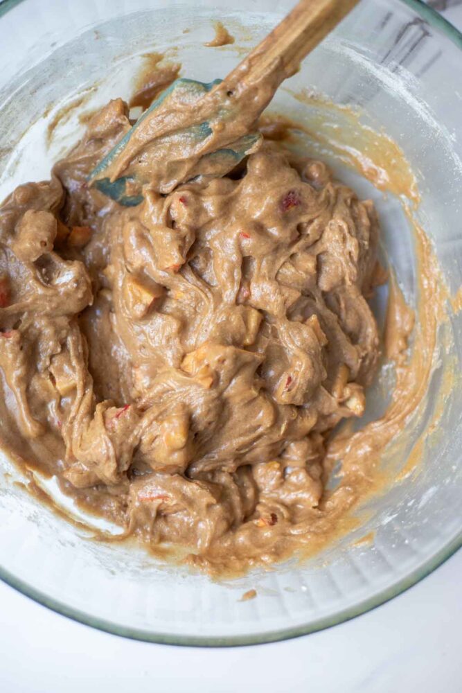 Gluten free apple muffin batter mixed in a glass bowl with a spatula.