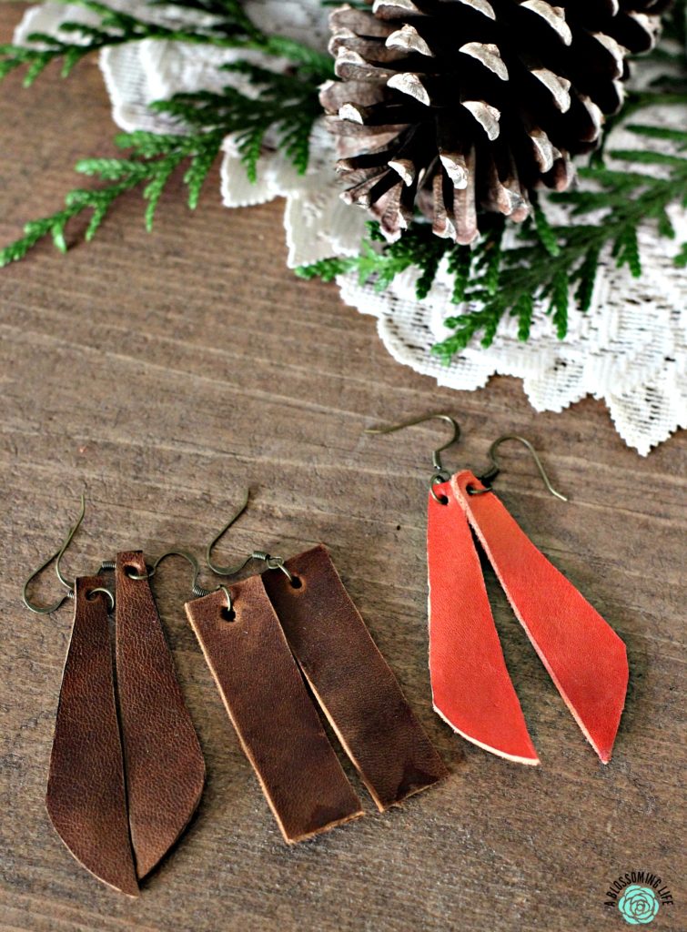 3 pairs of DIY leather earrings on a table with pine cone behind it