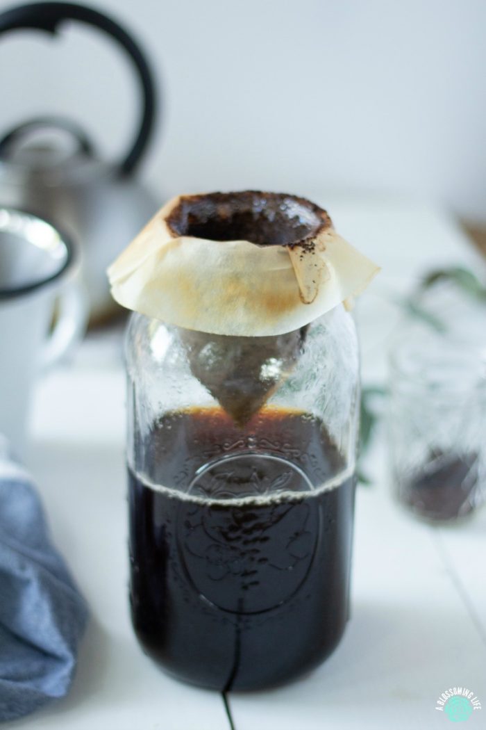 coffee being made in a half gallon wide mouth mason jar with a coffee filter over the wide mouth - how to make coffee without a coffee maker