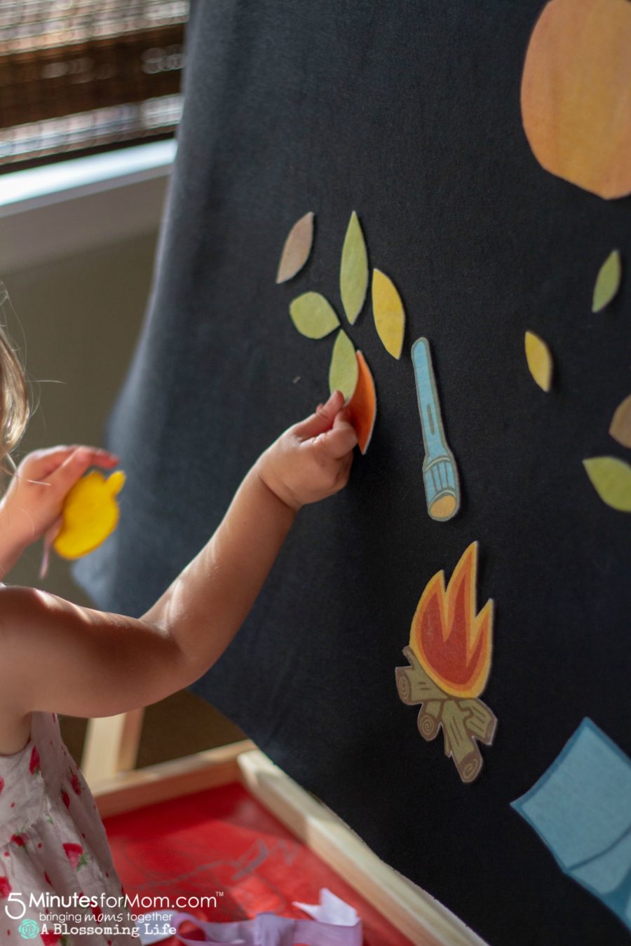 girl playing with a fall and camping themed felt board