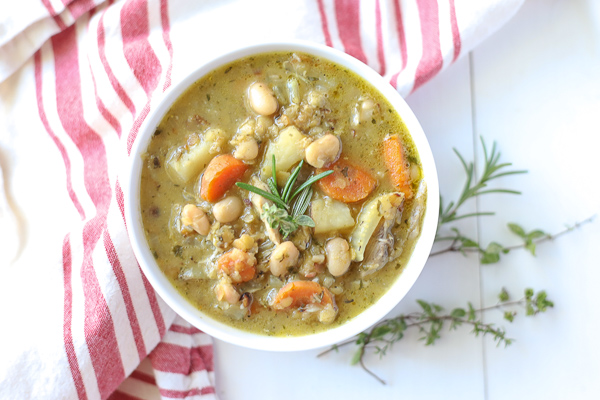 Bowl of chicken lentil soup that is full of carrots, potatoes, and beans in a nourishing chicken broth.