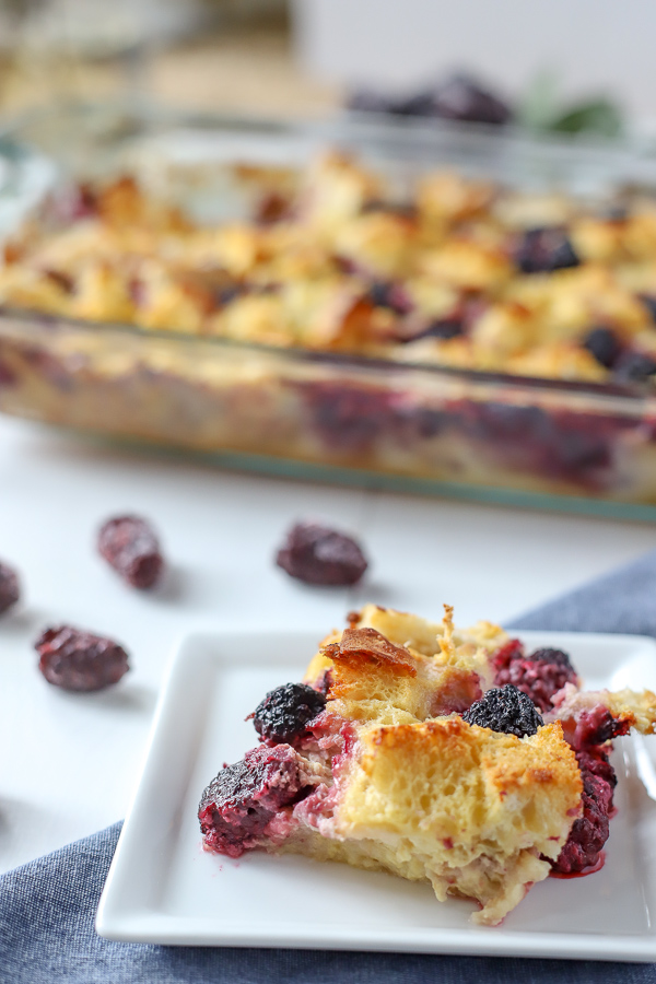 Slice of French Toast Casserole with Blackberries and a baking dish in the back