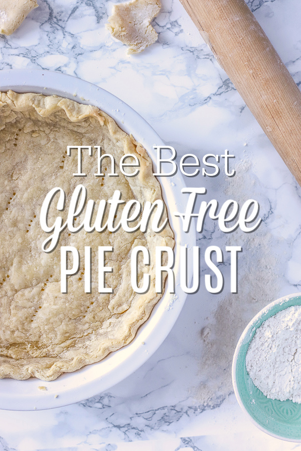 Gluten Free Pie Crust in a pie pan laying on a marble counter with a rolling pin and bowl of gluten free flour