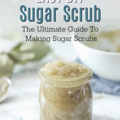 jar of sugar scrub on a marble countertop with an bowl of scrub behind it and dried eucalyptus