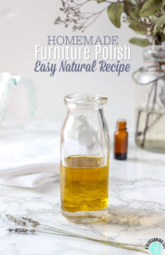 glass bottle of homemade furniture polish on a marble table with lavender flowers in front