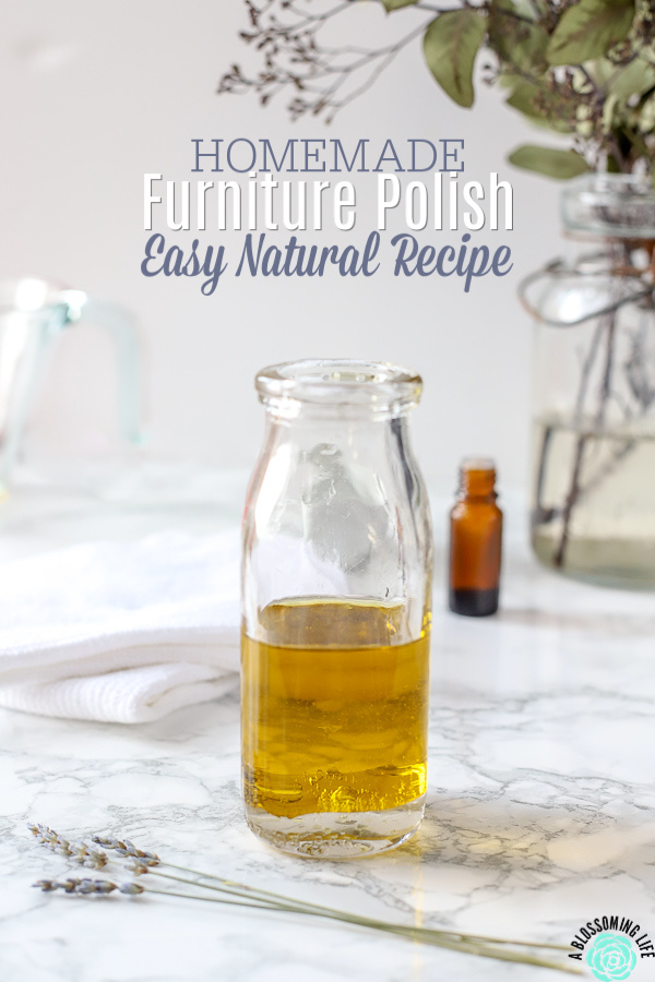 glass bottle of homemade furniture polish on a marble table with lavender flowers in front