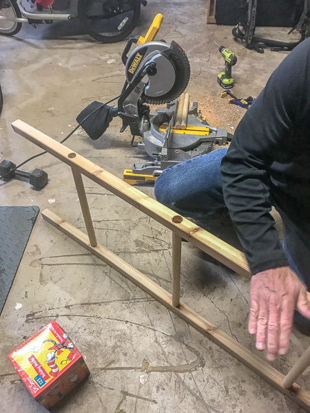 placing dowel rods into 2x2s to create diy blanket ladder