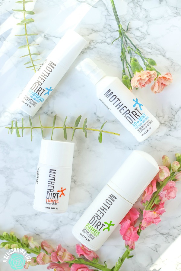 mother dirt probiotic skin care and biome-friendly products on a marble counter with flowers around them