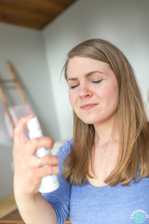 women in blue shirt spraying probiotics onto skin