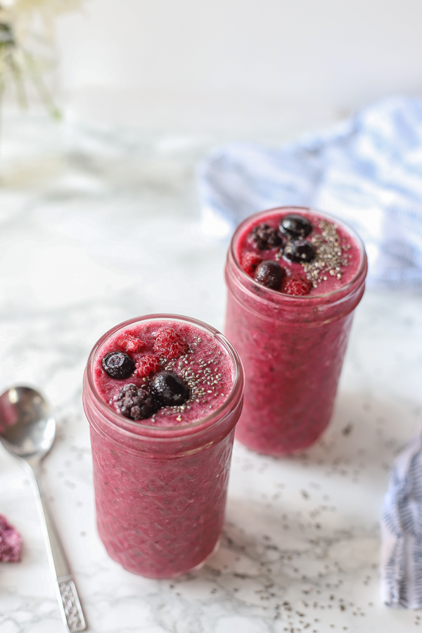 two berry beet smoothies on a marble counter top with blue and white napkin behind it