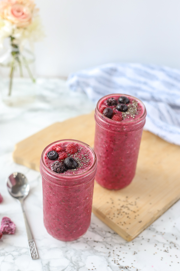 berry beet smoothie recipe on a marble countertop with a wood cutting board and ingredients around it