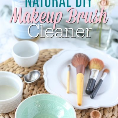 Natural DIY makeup brush cleaner in a teal bowl on a ratan placemat with makeup brushes and ingredients behind it